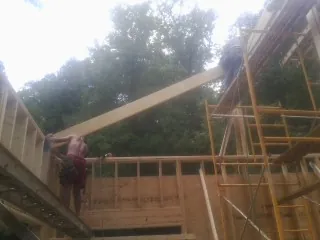 Carpenter raising a rafter beam on a new second story frame in Fredericktown