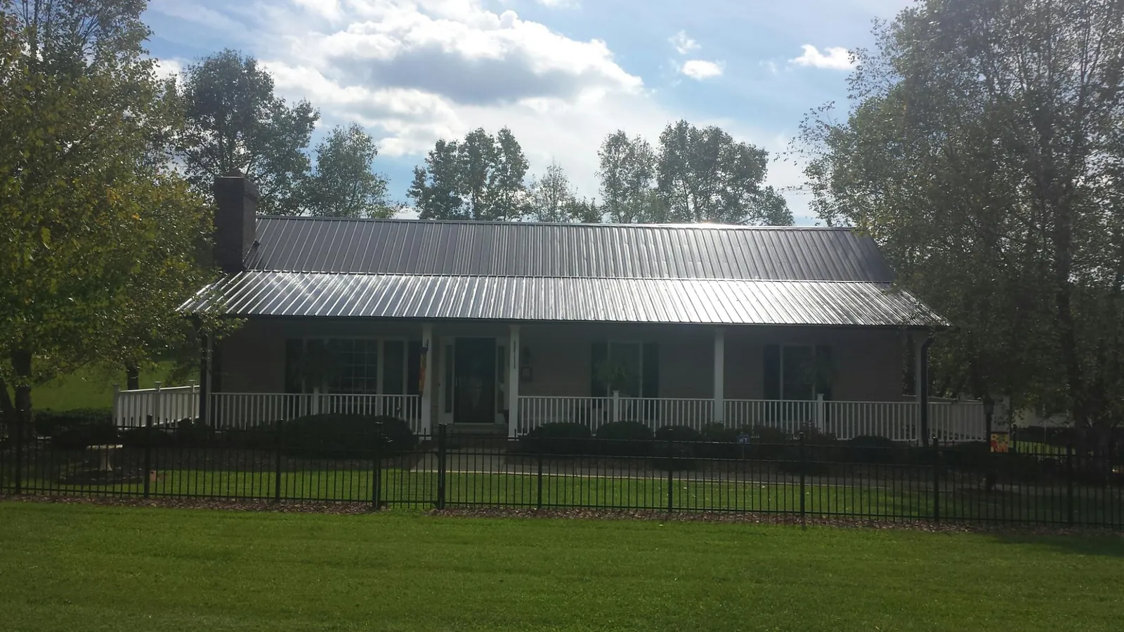 Gray metal roof on a brick ranch with a full width front porch — Gutter Guard Installation work by our crew in Fredericktown