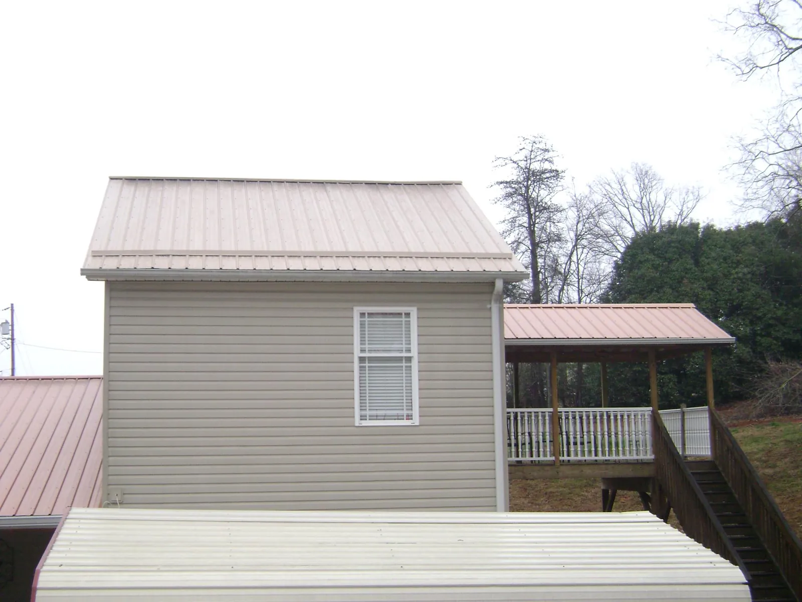 Tan metal roofs on a two story addition and attached porch, from a Roof Replacement job in Fredericktown