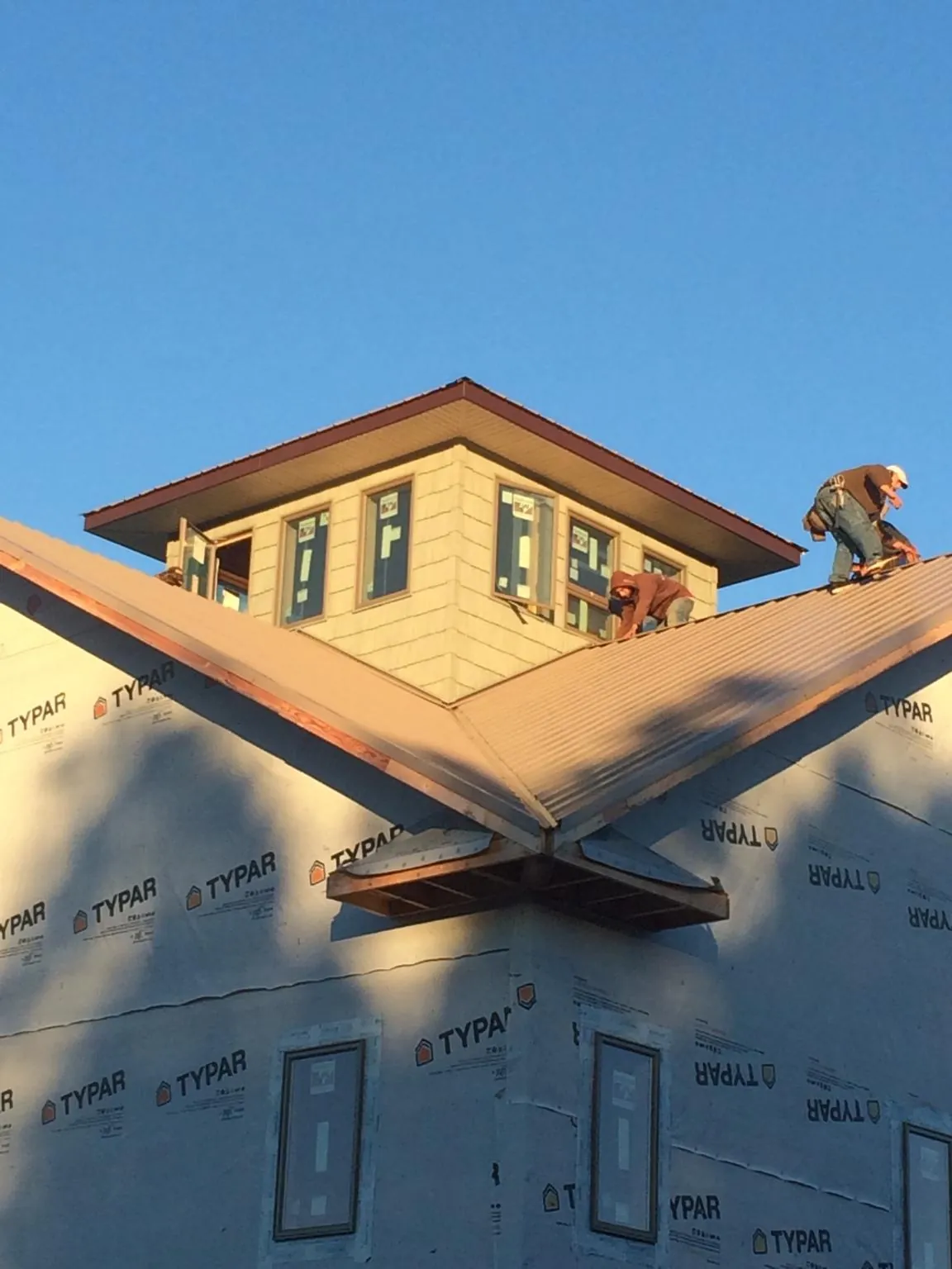 Roofers working around a rooftop cupola on a new metal roof at sunset — Roof Waterproofing in Fredericktown by Roofing Brothers